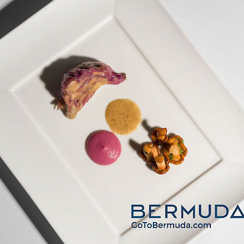 The image shows a plated dish with four types of food arranged artistically, accompanied by the text “Bermuda GoToBermuda.com.”