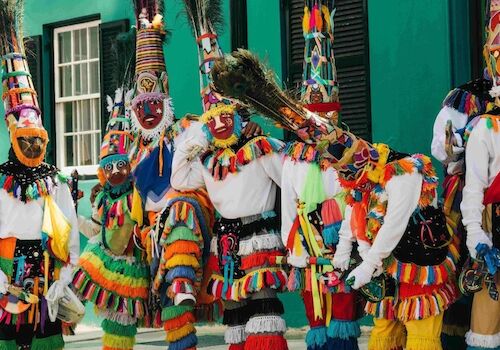 A group of people in colorful costumes and masks are gathered together, likely participating in a cultural festival or celebration.