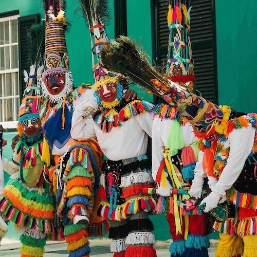 A group of people in colorful costumes and masks are gathered together, likely participating in a cultural festival or celebration.