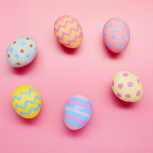 The image shows six colorful Easter eggs with various patterns on a pink background.